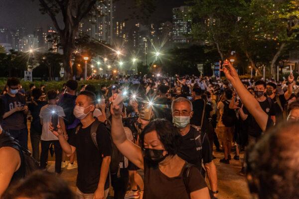 People hold up their lighted phones as they walk near the Victoria Park after police closed the venue where Hong Kong people traditionally gather annually to mourn the victims of China's Tiananmen Square Massacre in 1989, in the Causeway Bay district in Hong Kong, on June 4, 2021. (Anthony Kwan/Getty Images)