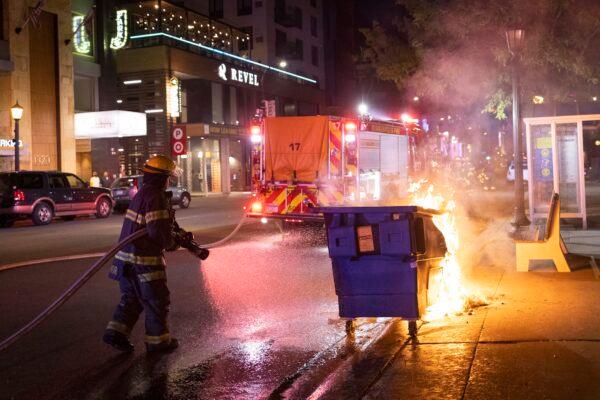 A firefighter puts out a dumpster fire after protesters clash with police in Minneapolis, Minn., on June 5, 2021. (Christian Monterrosa/AP Photo)