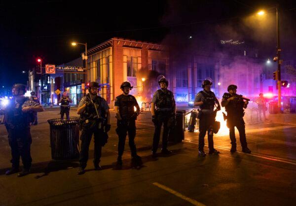Police stand guard after rioters set fire to dumpsters in Minneapolis, Minn., on June 5, 2021. (AP Photo/Christian Monterrosa)