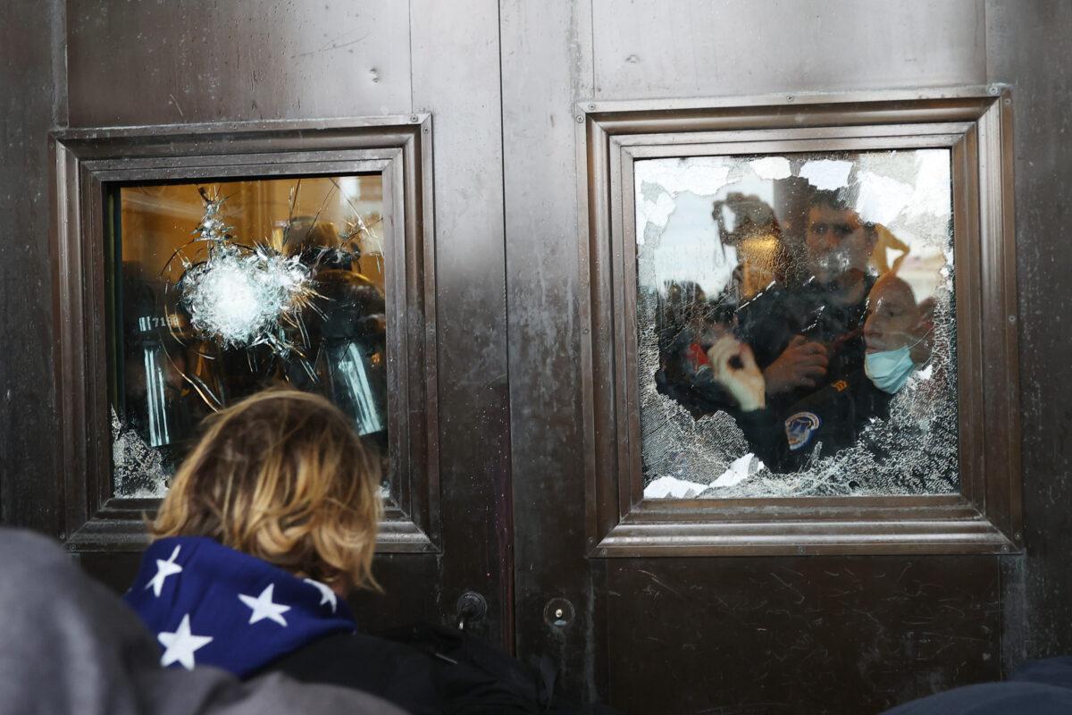 Capitol police officer looks out of a broken window as a crowd attempts to breach the U.S. Capitol in Washington on Jan. 6, 2021. (Tasos Katopodis/Getty Images)