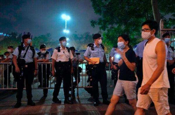 People hold candles and walk past police officers near Victoria Park, a place in the past years for people to gather during a candlelight vigil to mark the anniversary of the military massacre of a pro-democracy student movement in Beijing, in Hong Kong, on June 4, 2021. (Vincent Yu/AP Photo)
