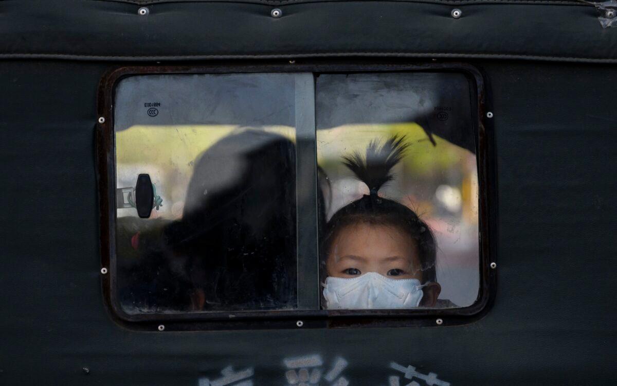 A Chinese girl looks out the back window of a three-wheeled taxi in the street in Beijing on April 22, 2020. (Kevin Frayer/Getty Images)