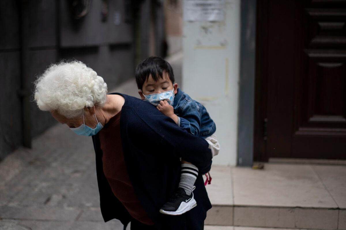 An elderly woman is carrying a boy along a street in Beijing on May 11, 2020. (Noel Celis/AFP via Getty Images)