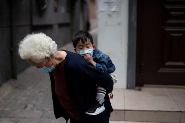 An elderly woman is piggybacking a boy along a street in Beijing on May 11, 2020. (Noel Celis/AFP via Getty Images)