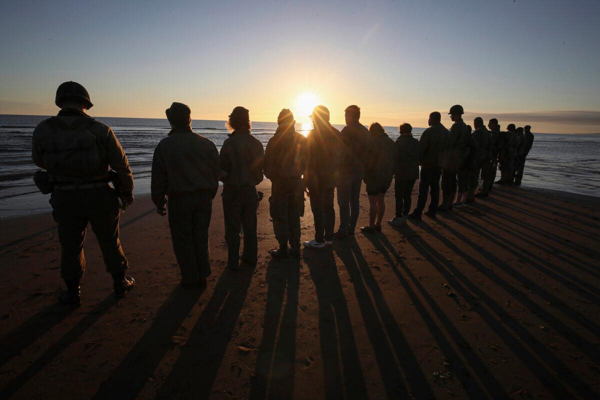 World War II reenactors pay tribute to soldiers at dawn at the shore of Omaha Beach in Saint-Laurent-sur-Mer, Normandy, France, on June, 6 2021. (David Vincent/AP Photo)