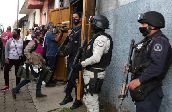 Police officers and members of the National Guard stand guard as workers of the National Electoral Institute (INE) carry voting materials, to be distributed to polling stations, ahead of midterm elections in Nahuatzen, Mexico, on June 5, 2021. (Alan Ortega/Reuters)