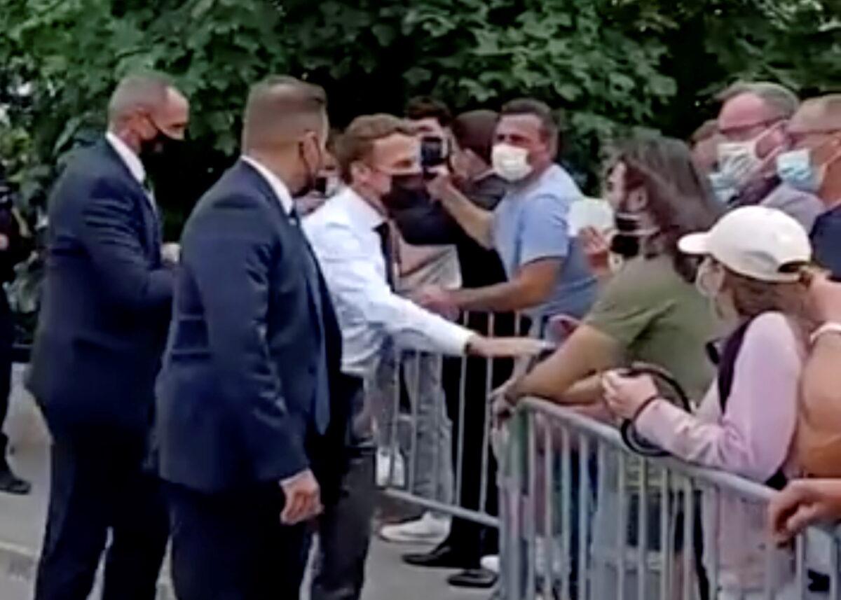 French President Emmanuel Macron speaks with a member of the public before he was slapped during a visit in Tain-L'Hermitage, France, in this still image taken from video, on June 8, 2021. (BFMTV/ReutersTV via Reuters)