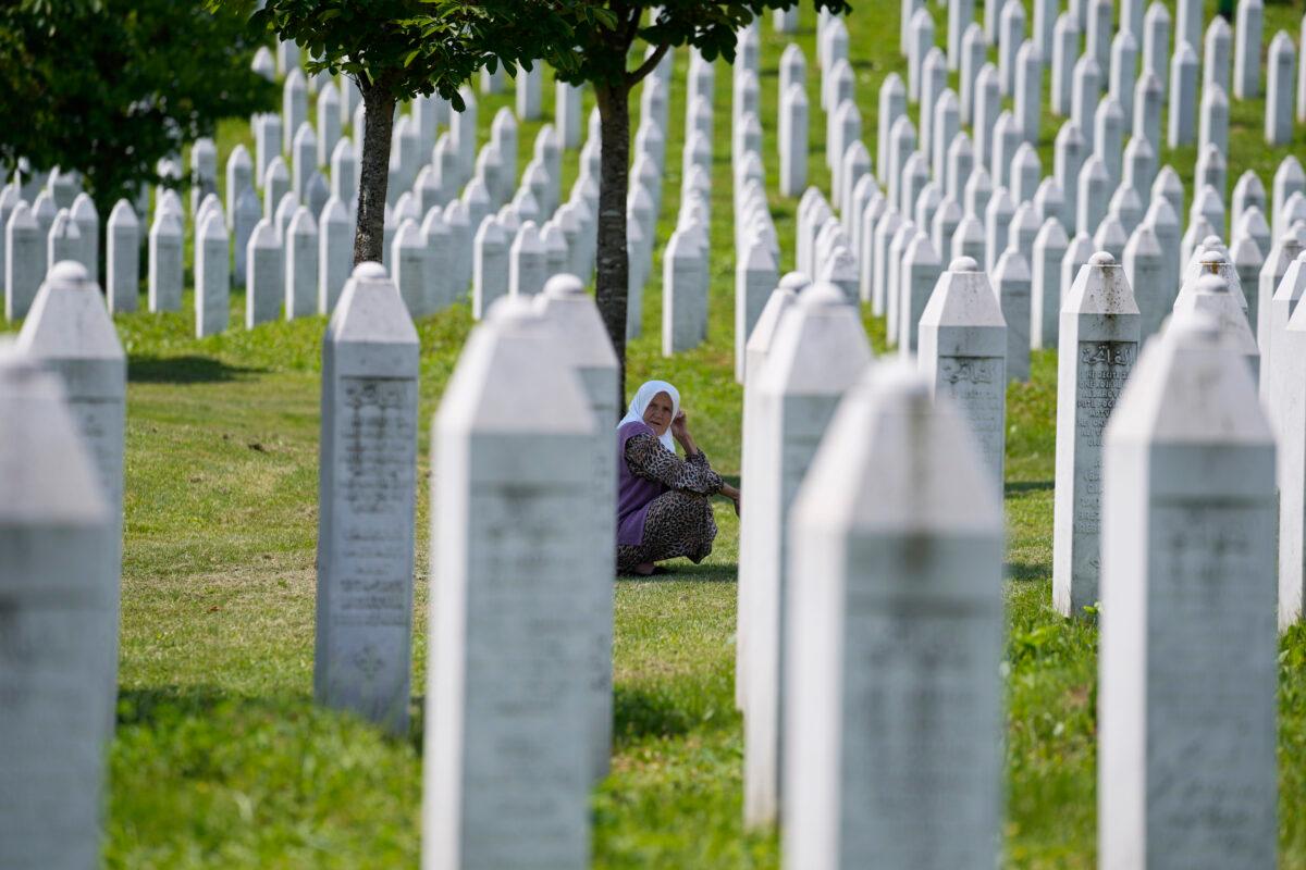 A woman crouches among the graves of victims of the Srebrenica massacre, at the memorial cemetery in Potocari, near Srebrenica, eastern Bosnia, Tuesday, June 8, 2021. (Darko Bandic/AP Photo)