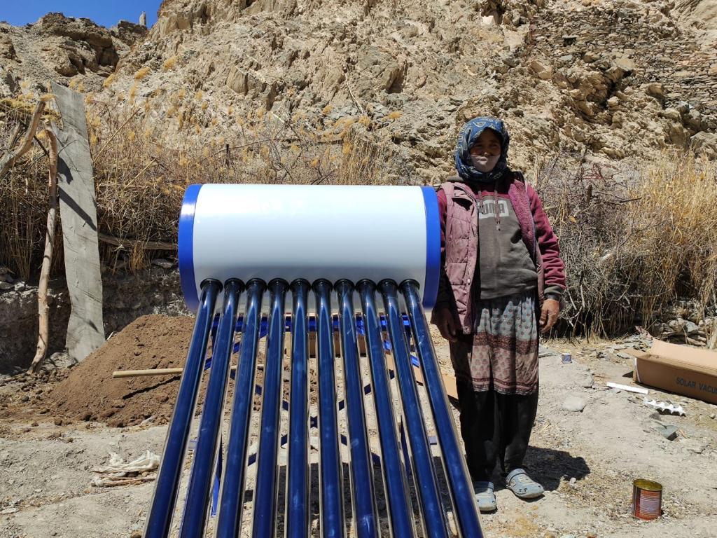 A Ladakhi woman with her newly installed solar water heater in the village of Chalak in the Ladakh region of India in April 2021. The installation was done by the engineers of the Global Himalayan Expedition (GHE), an Indian social enterprise. (Picture courtesy GHE)