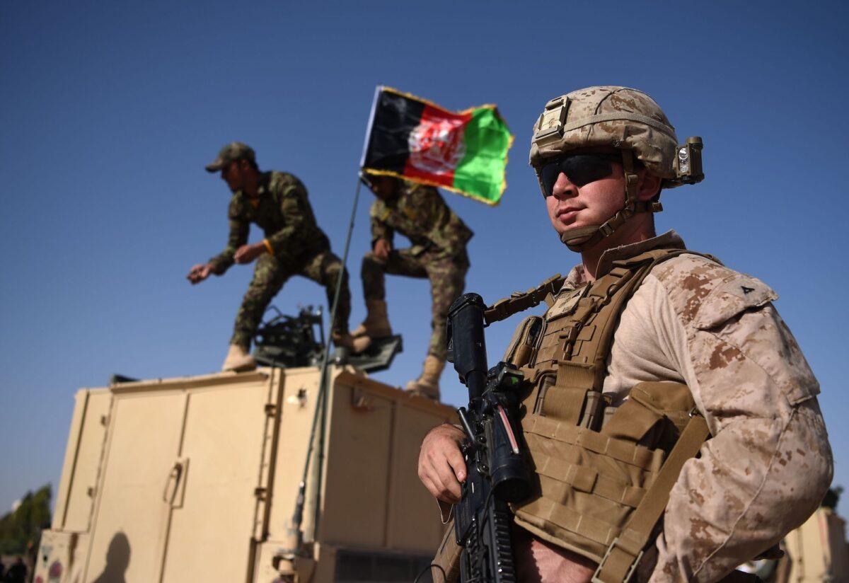 A U.S. Marine looks on as Afghan National Army soldiers raise the Afghan National flag on an armed vehicle during a training exercise at the Shorab Military Camp in Helmand Province, Afghanistan, on August 28, 2017. (Wakil/Koshar/AFP via Getty Images)