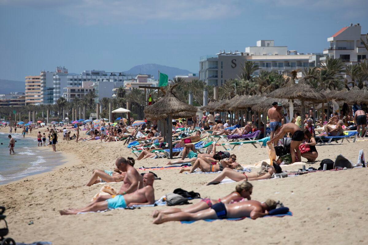Tourists sunbathe on the beach at the Spanish Balearic Island of Mallorca, Spain, on June 7, 2021. (Francisco Ubilla/AP Photo)