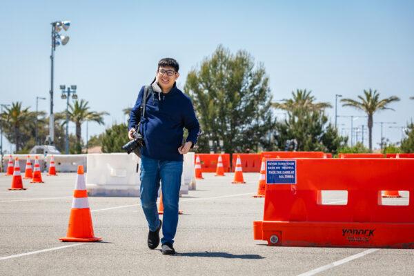 Photographer John Uy walks through a parking lot at the COVID vaccination site in Irvine, Calif., on May 7, 2021. (John Fredricks/The Epoch Times)