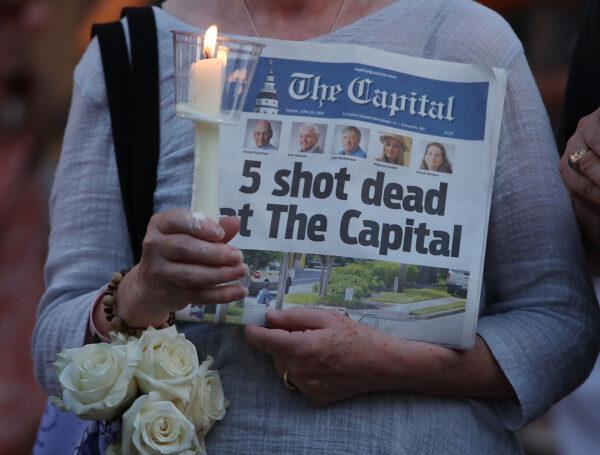 A woman holds today's edition of the Capital Gazette newspaper during a candlelight vigil to honor the 5 people who were shot and killed the day before, in Annapolis, Md., on June 29, 2018. (Mark Wilson/Getty Images)