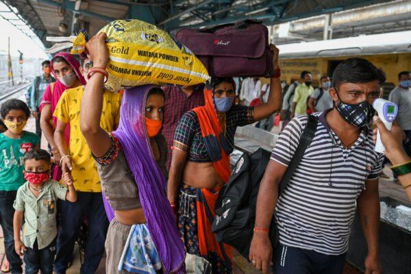 A health worker checks the body temperature of a passenger during a COVID-19 screening as he arrives at a railway platform on a long distance train, in Mumbai, India, on June 8, 2021. (Punit Paranjpe/AFP via Getty Images)