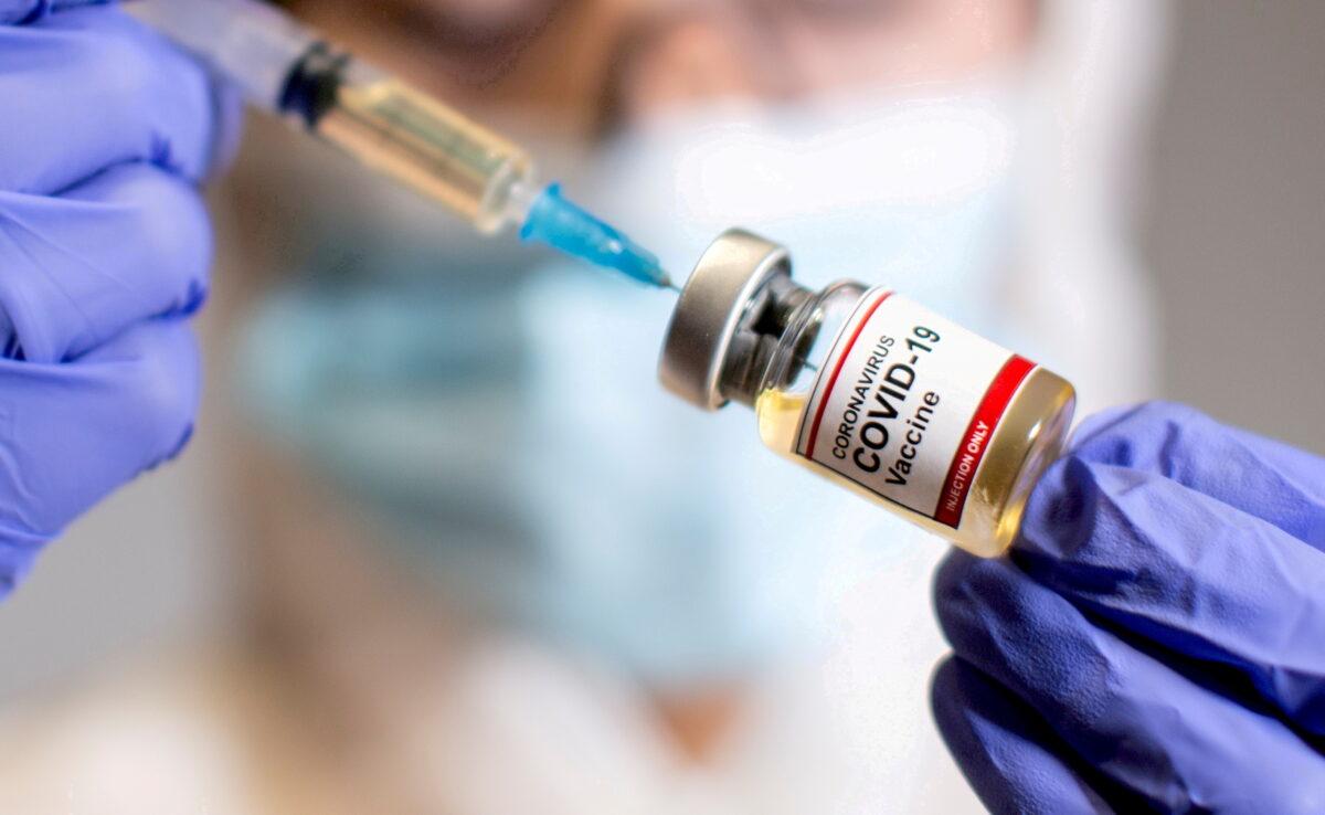 A woman holds a small bottle labelled with a "Coronavirus COVID-19 Vaccine" sticker and a medical syringe in this illustration taken on Oct. 30, 2020. (Dado Ruvic/Reuters)
