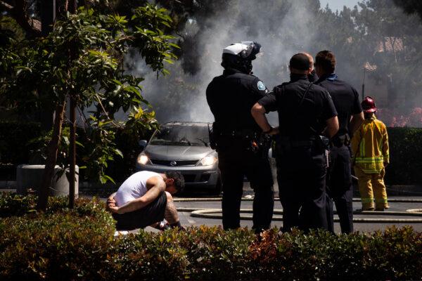 Orange County Fire Authority firefighters extinguish flames from a car that ignited. A suspect said to be under the influence of drugs was taken into custody by Irvine Police Department officers in Irvine Calif., on June 11, 2021. (John Fredricks/The Epoch Times)