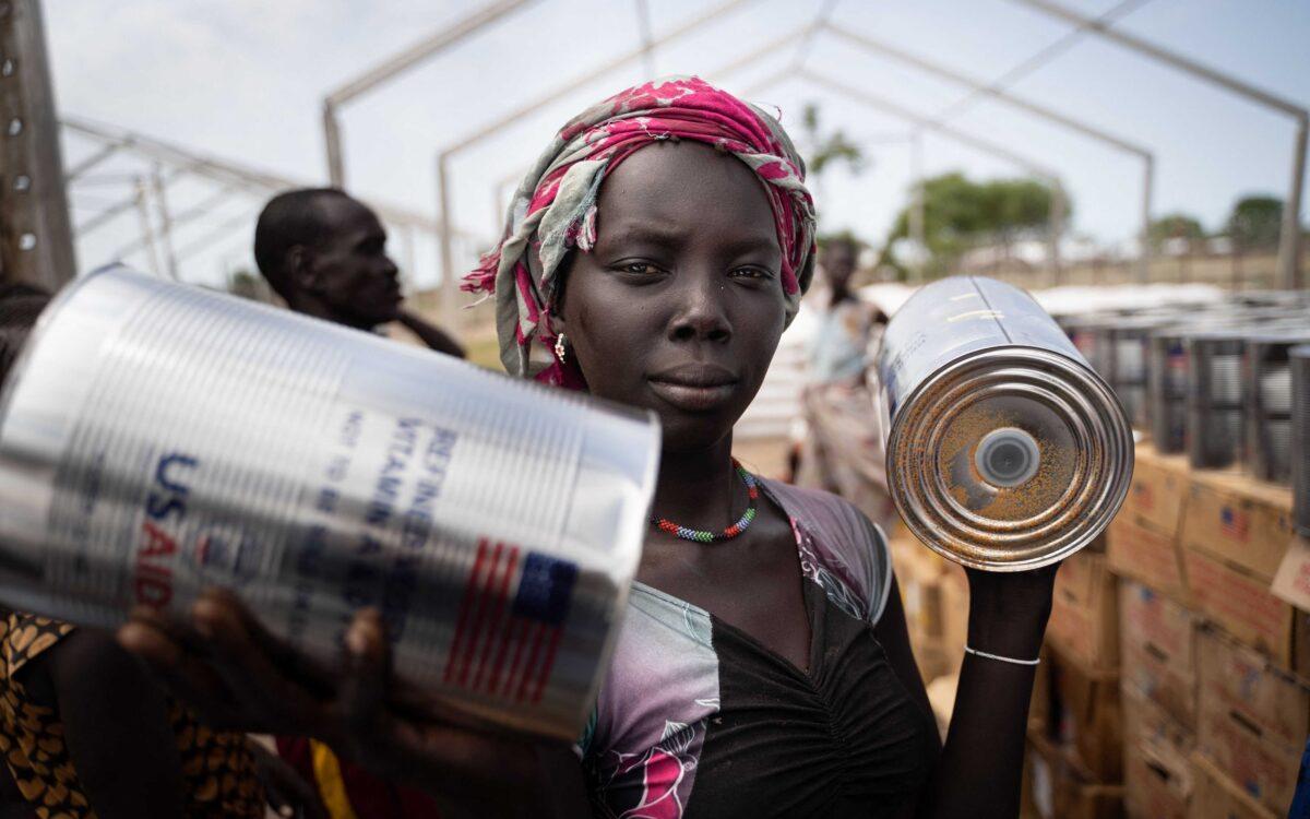 A woman from the Murle ethnic group receives cans of oil during a food distribution by United Nations World Food Programme (WFP) in Gumuruk, South Sudan, on June 10, 2021, after her village was attacked by an armed youth group. (Simon Wohlfahrt/AFP via Getty Images)