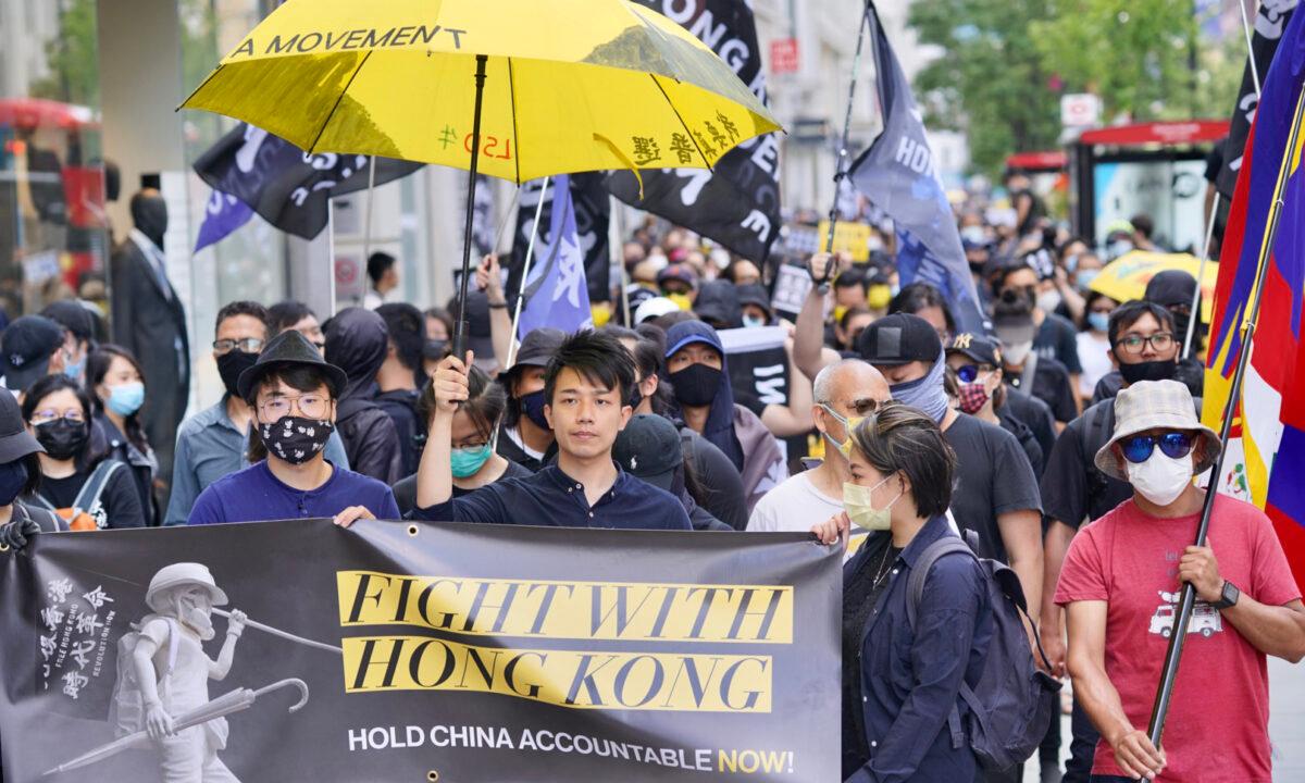 Simon Cheng (front left) and Finn Lau (centre) in a march commemorating the two-year anniversary of Hong Kong's pro-democracy movement in London on June 12, 2021. (Yanning Qi/The Epoch Times)