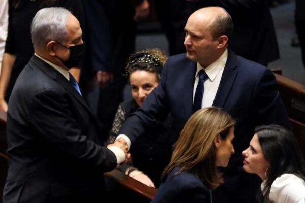 Head of Opposition Benjamin Netanyahu (L) and Israeli Prime minister Naftali Bennett (R) shake hands following the vote on the new coalition at the Knesset, Israel's parliament, in Jerusalem, on June 13, 2021. (Ronen Zvulun/Reuters)