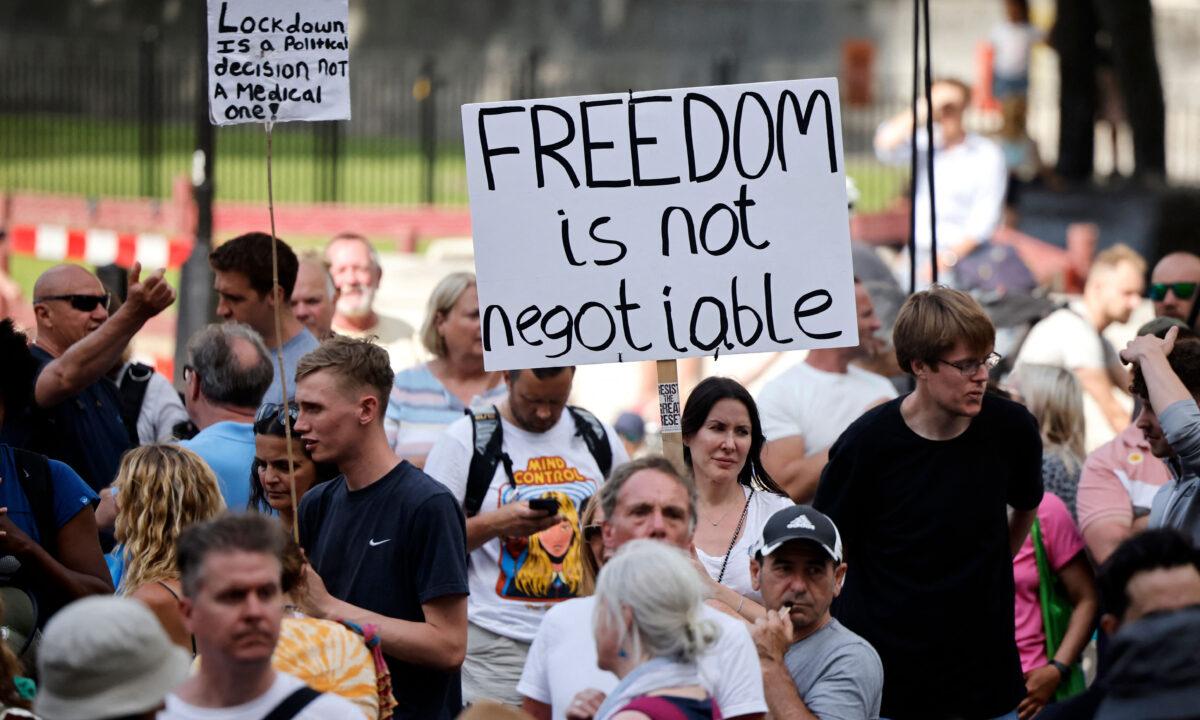 Protesters hold up placards at a demonstration against government lockdown restrictions in Parliament Square in central London on June 14, 2021. (Tolga Akmen/AFP via Getty Images)
