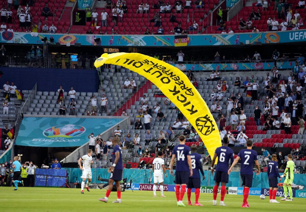 A Greenpeace paraglider lands on the pitch before the Euro 2020 soccer championship group F match between France and Germany at the Allianz Arena in Munich, Germany, on June 15, 2021. (Matthias Schrader/Pool/AP Photo)