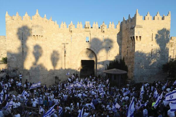  Jewish people waving Israeli flags participate in the Flags March next to Damascus Gate, outside Jerusalem's Old City, on June 15, 2021. (Mahmoud Illean/AP Photo)