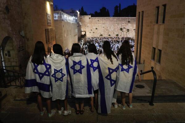  Jewish people covered with Israeli flags participate in the Flags March next to the Western Wall, the holiest site where Jews go to pray, in the Old City of Jerusalem, June 15, 2021. (Maya Alleruzzo/AP Photo)