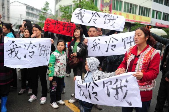 Residents in Lingguan township of Baoxing county gather on the street with banners saying "I am cold and hungry" to appeal for support and attention about the relief supply shortage after the earthquake in China's Sichuan Province on April 23, 2013. (STR/AFP via Getty Images)