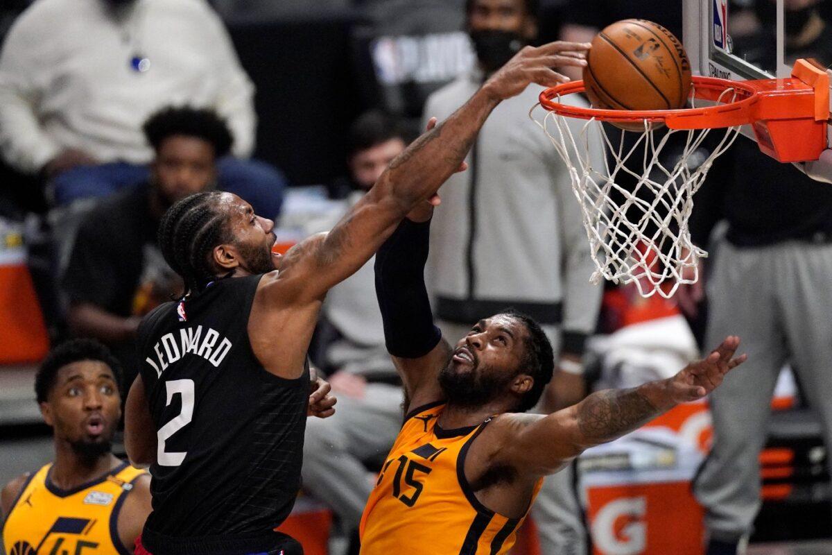 Los Angeles Clippers forward Kawhi Leonard, center, dunks over Utah Jazz center Derrick Favors, right, as guard Donovan Mitchell watches during the first half in Game 4 of a second-round NBA basketball playoff series in Los Angeles, Calif., on June 14, 2021. (Mark J. Terrill/AP Photo)