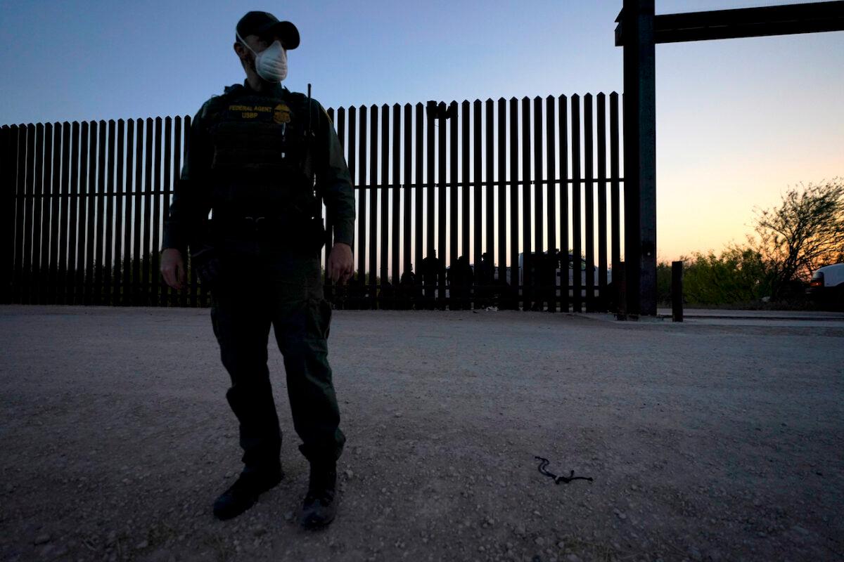 A U.S. border agent looks on near a gate on the U.S.–Mexico border wall, in Abram-Perezville, Texas, in this file photo. (Julio Cortez/AP Photo)