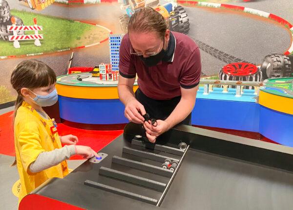 Abigail and her father Chris build Lego cars and race them at a build station at Legoland Discovery Center Bay Area in the Great Mall in Milpitas, Calif., on June 14, 2021. (Ilene Eng/The Epoch Times)