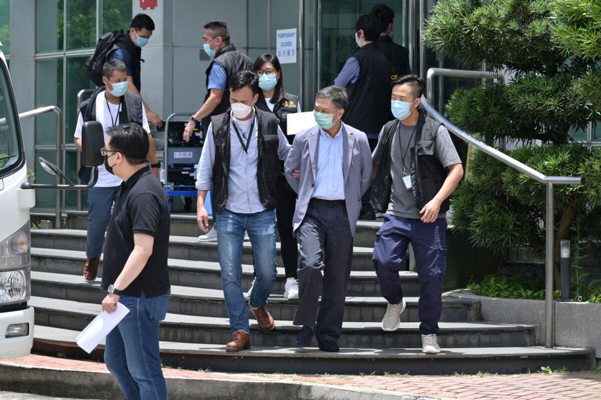 Chief Operations Officer Chow Tat Kuen (front 2nd-R) is escorted by police from the Apple Daily newspaper offices before being put into a waiting vehicle in Hong Kong, on June 17, 2021. (Anthony Wallace/AFP via Getty Images)