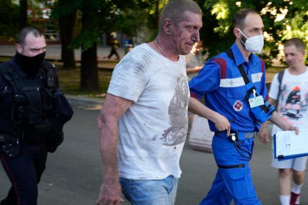 A Russian Emergency Situations Ministry paramedic, right, and a police officer escort a wounded man from a fire place at a warehouse in Moscow, Russia, June 19, 2021. (Pavel Golovkin/AP Photo)