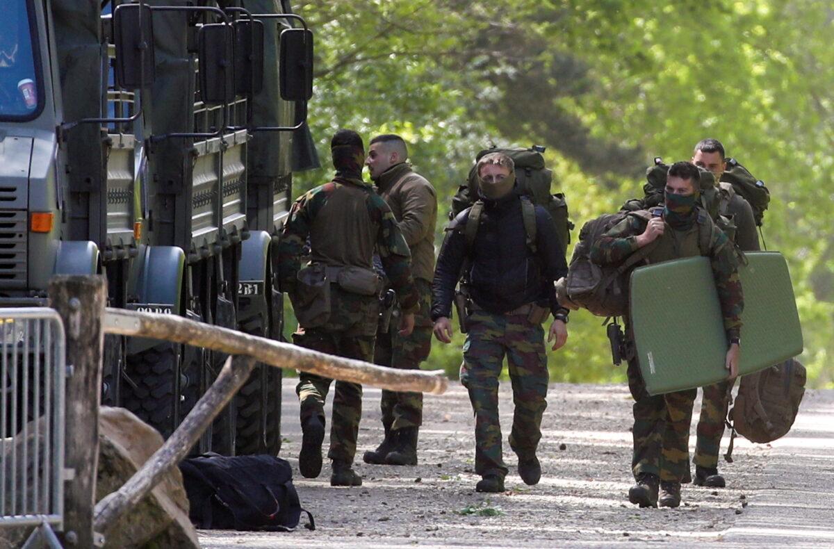 Belgian army members carry their bags at National Park Hoge Kempen while scouring to capture Belgian Jurgen Conings, a soldier who disappeared after threatening a virologist supportive COVID-19 vaccines and coronavirus restrictions, in Maasmechelen, Belgium, on May 21, 2021. (Yves Herman/Reuters)
