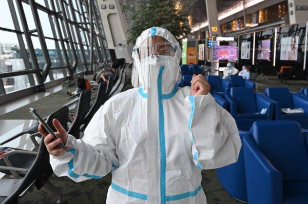 A Chinese passenger bound for Shenzhen, China, puts on personal protective equipment (PPE) before getting in line for a plane at the Sukarno Hatta international airport in Tangerang, Indonesia, on June 8, 2021. (ADEK BERRY/AFP via Getty Images)