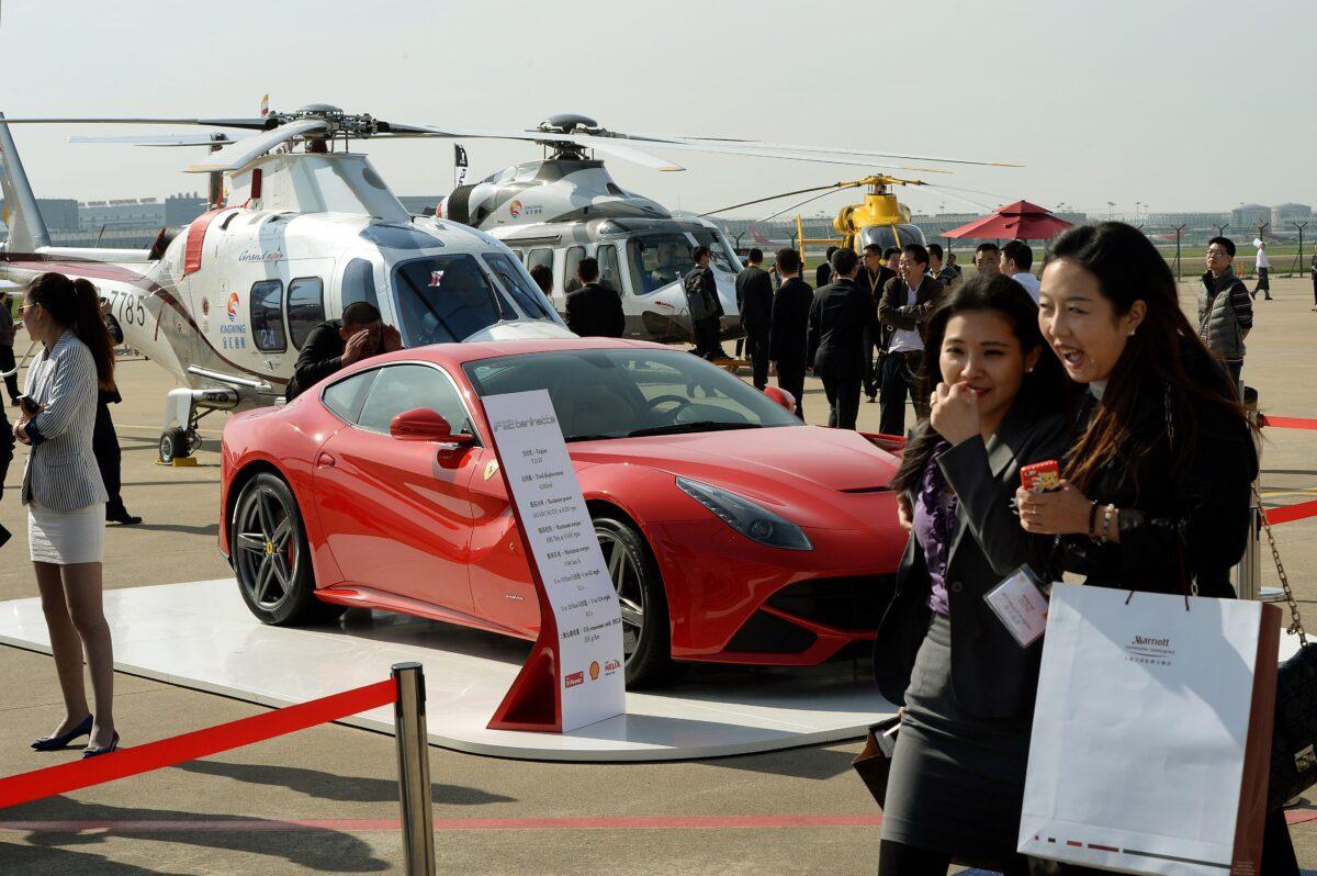 People walk past a Ferrari car and helicopters that global companies are marketing to wealthy Chinese during the Asian Business Aviation Conference and Exhibition (ABACE2014) at the Shanghai Hongqiao airport, China, on April 14, 2014. (Mark Ralston/AFP via Getty Images)