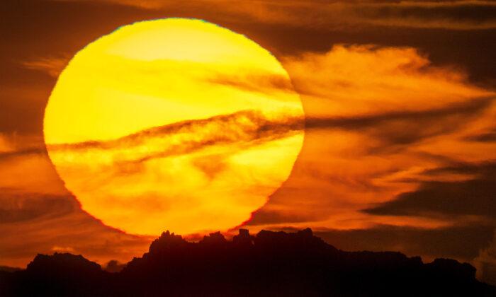 Photographer Captures Surreal Sight of Huge Raging Sun Setting Behind Iconic Rock Formation in UK
