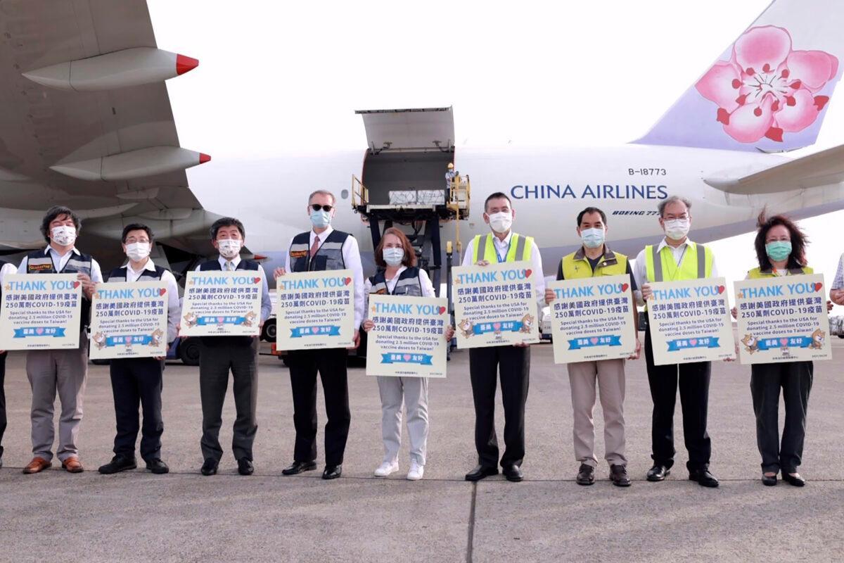 Taiwan's Health Minister Chen Shih-chung (3rd-L) and Brent Christensen, the top U.S. official in Taiwan (4th-L) hold up thank you cards as they welcome a China Airlines cargo plane carrying COVID-19 vaccines from Memphis that arrived at the airport outside Taipei in Taiwan, on June 20, 2021. (Taiwan Centers for Disease Control via AP)
