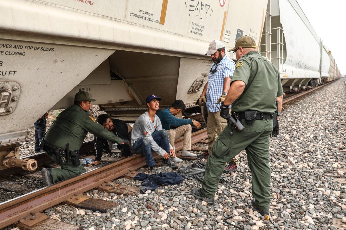 Border Patrol agents apprehend illegal aliens from Mexico as they exit from the bottom of a grain hopper on a freight train heading to San Antonio, on June 21, 2021. (Charlotte Cuthbertson/The Epoch Times)