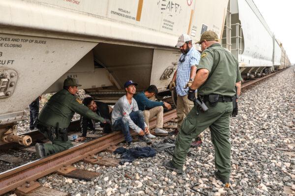 Border Patrol agents apprehend illegal aliens from Mexico as they exit from the bottom of a grain hopper on a freight train heading to San Antonio, near Uvalde, Texas, on June 21, 2021. (Charlotte Cuthbertson/The Epoch Times)