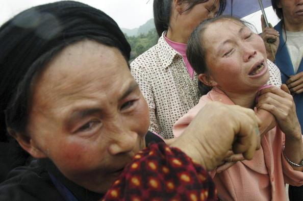  Family members cry during the funeral of a victim killed by a reservoir collapse in Yiliang County of Yunnan Province, southwest China on July 22, 2005. (China Photos/Getty Images)