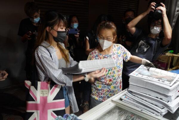 A woman buys multiple copies of Apple Daily at a newsstand at Mong Kok in Hong Kong on June 24, 2021. (Andrian Yu/The Epoch Times)