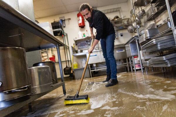 Slapfish cofounder and executive chef Andrew Gruel washes floors at the Huntington Beach, Calif., location on June 7, 2021. (John Fredricks/The Epoch Times)