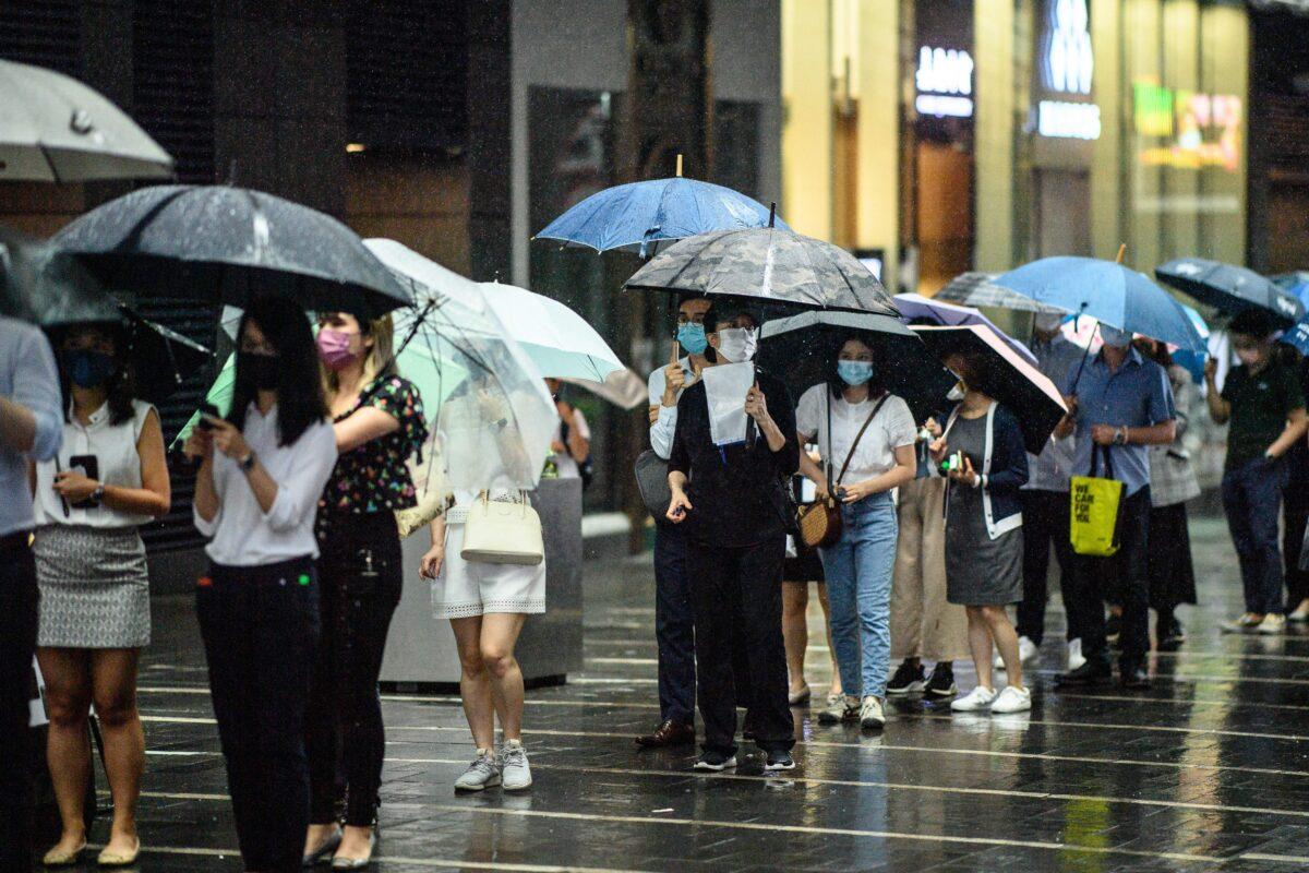People line up in the rain up to buy the Apple Daily newspaper's final issue from a newsstand in Hong Kong on June 24, 2021, (Anthony Wallace/AFP via Getty Images)