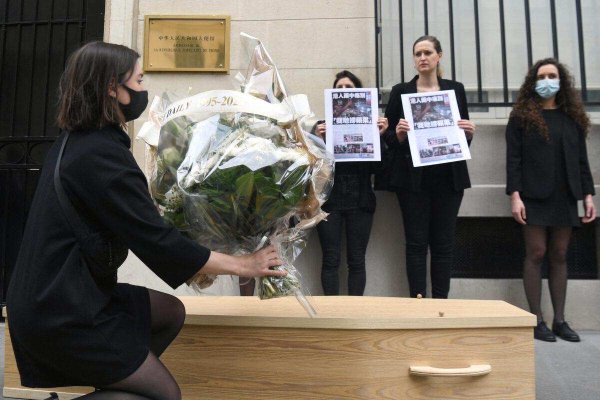 A protester lays flowers on the ground at China's embassy in Paris, on June 25, 2021, in support of Apple Daily, a pro-democracy tabloid that was forced to close under Hong Kong's new national security law. (ALAIN JOCARD/AFP via Getty Images)