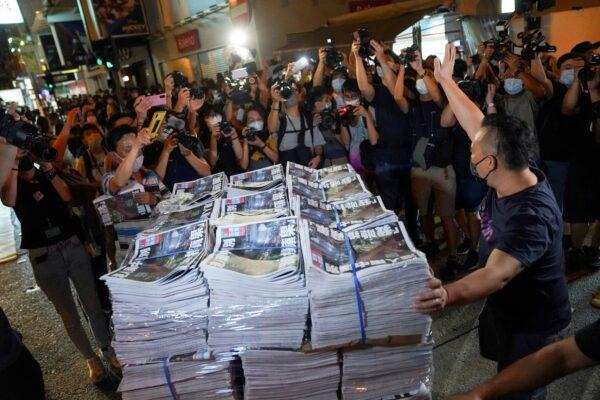 A man gestures as he brings copies of the final edition of Apple Daily, published by Next Digital, to a news stand in Hong Kong, on June 24, 2021. (Lam Yik/Reuters)