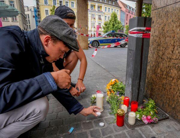 Flowers and candles are laid by young men at the crime scene in central Wuerzburg, Germany, on June 26, 2021. (Michael Probst/AP Photo)