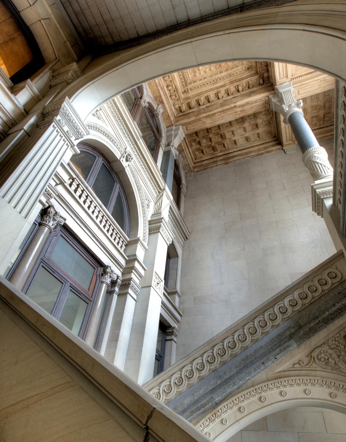 This portal stairwell is made of limestone walls, with granite for the steps, columns, and base, and limestone for the heavy carved railings. The stairwell provides access to the upper levels while allowing natural light to penetrate deep into the building. (Bestbudbrian/CC BY-SA 3.0)