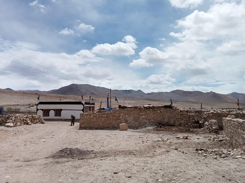 The hunched figure of Tseten Namgyal, 82, next to his old stone-mud home in the village of Urgu, on the de-facto India-China border in the union territory of Ladakh on June 22, 2021. (Venus Upadhayaya/Epoch Times)