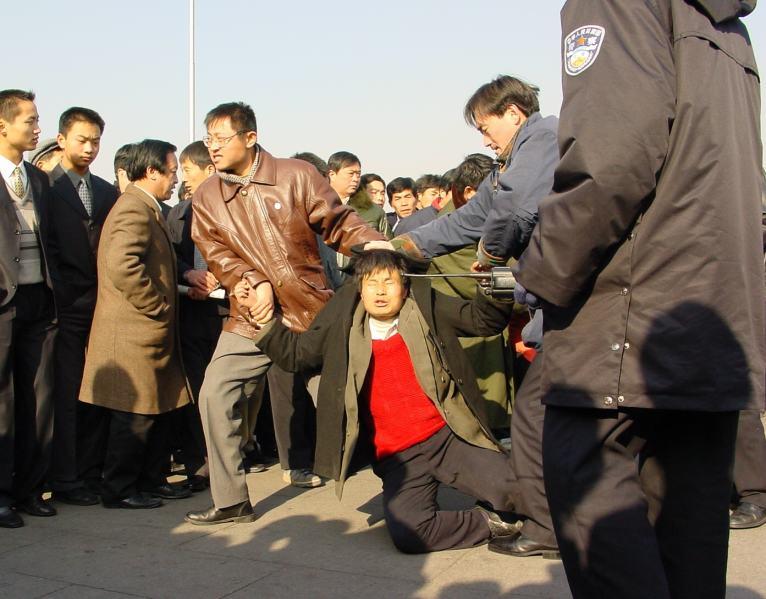 Two plainclothes police officers arrest a Falun Gong practitioner at Tiananmen Square in Beijing, on Dec. 31, 2000. (Minghui.org)